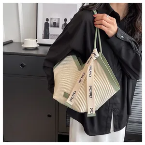 Close-up of pleated canvas tote bag with contrast trim and branded ribbon detail