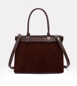 Detail of dark brown tote bag with matte texture, leather handles and adjustable shoulder strap