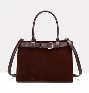 Detailed shot of dark brown frosted suede handbag with smooth leather belt and silver buckle