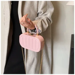 Close-up of pink chain crossbody bag with vertical striped embossing and golden hardware