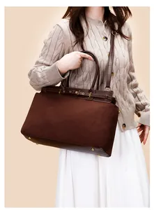 Detail of dark brown suede tote bag featuring golden metal protective base studs and smooth leather