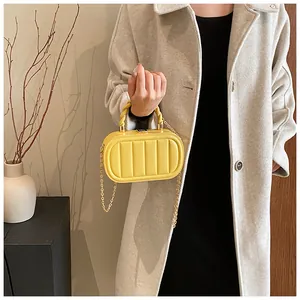 Detail of yellow oval crossbody bag with vertical quilted texture and gold spiral handle
