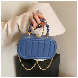 Close-up of blue oval bag with vertical pleats, woven handle and gold chain strap