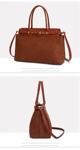 Detail view of brown matte tote bag with decorative gold buckle strap and sleek handles