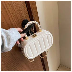 Detail of white quilted crossbody bag with golden chain and woven handle on door handle