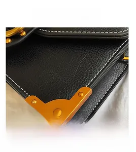 Macro detail of black lychee leather bag with gold rivets and metallic corner guard