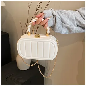 Detail of creamy white quilted clutch bag featuring unique spiral woven handle and gold clasp