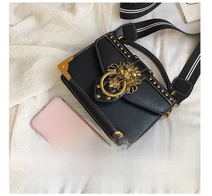 Detail of square leather bag with gold lion hardware and striped textile strap