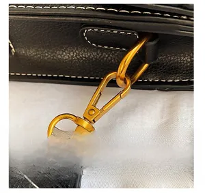 Detail of detachable shoulder strap with gold lobster clasp and white contrast stitching