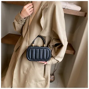 Detail of black pleated leather crossbody bag with woven handle and gold chain strap