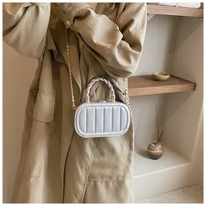 Detail of silver oval mini bag with vertical stripes and woven handle held by a model