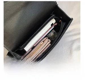 Detail showing high-capacity interior of black pebbled leather bag with zipper pocket