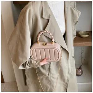 Detail view of beige pleated crossbody bag with twisted handle and gold chain strap