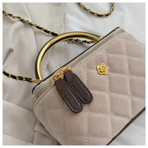 Detalle de bolso acolchado de ante con cierre de flor dorada y asa metálica elegante