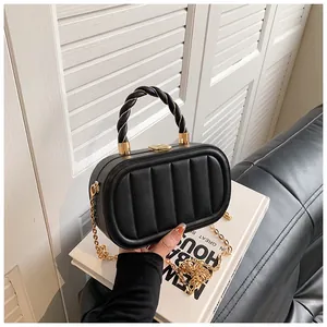 Detail of black PU leather box bag with vertical quilting and twisted top handle