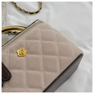 Detalle del diseño acolchado de gamuza y el adorno de camelia dorada en el bolso de mujer