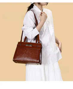 Detail of brown crocodile pattern handbag with silver metal buckle and top handles