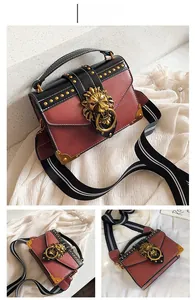 Detail of pink and black leather handbag featuring golden lion head buckle and rivets