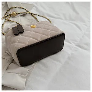 Detalle de bolso acolchado con camelia dorada y correa de cadena metálica