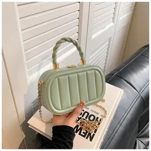 Detail view of mint green quilted handbag with woven handle and gold chain strap