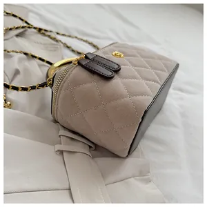 Detalle de bolso bandolera de ante acolchado con cadena dorada y cierre de doble cremallera