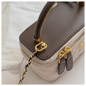 Detalle de la textura acolchada y los herrajes metálicos dorados del bolso de hombro