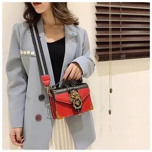 Detail of retro small square bag with golden lion buckle and studded metal corners