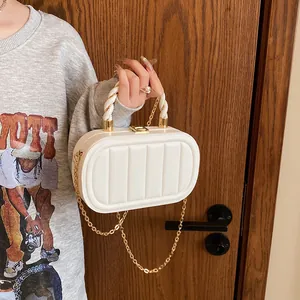 White quilted box clutch bag with gold chain strap and top handle shown on a model