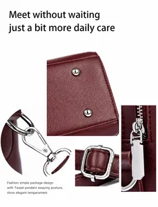 Details einer weinroten Handtasche aus Leder mit silbernen Nieten und verstellbarer Schnalle