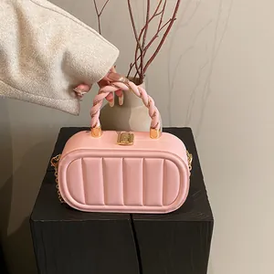 Pink quilted crossbody bag with woven handle and gold hardware on minimalist pedestal