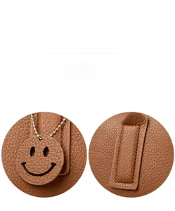 Close-up of litchi grain leather Boston bag with smiley face charm and fine stitching