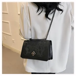 Détail du sac bandoulière noir avec texture écailles et chaîne en métal foncé