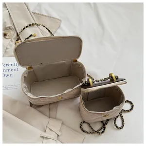 Detalle de bolsos acolchados beige en dos tamaños con cadena dorada y forro interior