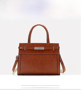 Detail of dark brown faux leather handbag with snake pattern texture and metal buckle clasp