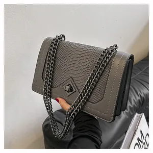 Détail du sac gris à chaîne avec rabat texture serpent et coutures blanches contrastées
