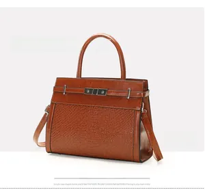 Close-up of brown crocodile texture handbag with gold metal clasp and leather straps
