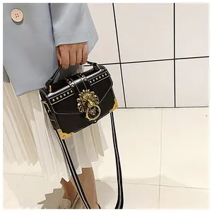 Chic black crossbody bag with gold lion head hardware and rivets shown on a model