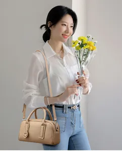 Close-up of beige lychee textured Boston bag with a cute smiley face leather charm detail