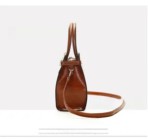 Side view of brown leather handbag featuring glossy oil wax texture and silver hardware