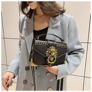 Detail of vintage black crossbody bag with gold lion head and metallic rivets