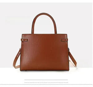 Close-up of brown textured leather tote bag showing handle details and adjustable straps