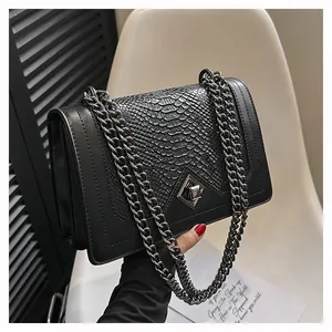 Détail du rabat motif serpent noir et du fermoir rotatif argenté sur le sac à bandoulière