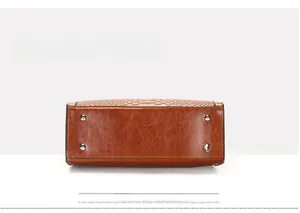 Detailed bottom view of brown handbag featuring silver protective studs and snakeskin texture