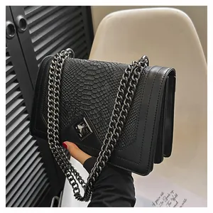 Détail du sac noir à texture écailles avec chaîne dorée et soufflets en accordéon