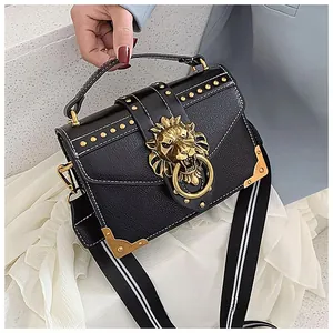 Detail of black leather bag with gold lion head buckle and studded edge decoration