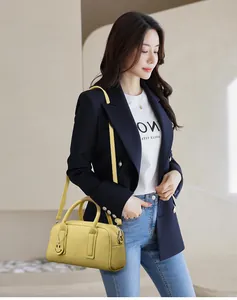 Detail of yellow pebbled leather tote bag with smile charm on a dark blazer outfit
