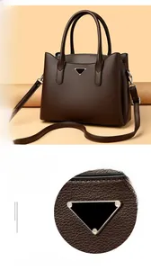 Détails du logo triangulaire argenté et du cuir grainé du sac à main marron