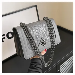 Détail du sac chaîne gris avec texture serpent, design en accordéon et fermoir métallique