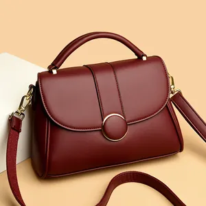 Elegant burgundy leather handbag with golden hardware and wide crossbody strap