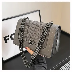 Détail de la texture serpent et du fermoir rotatif sur sac à bandoulière chic